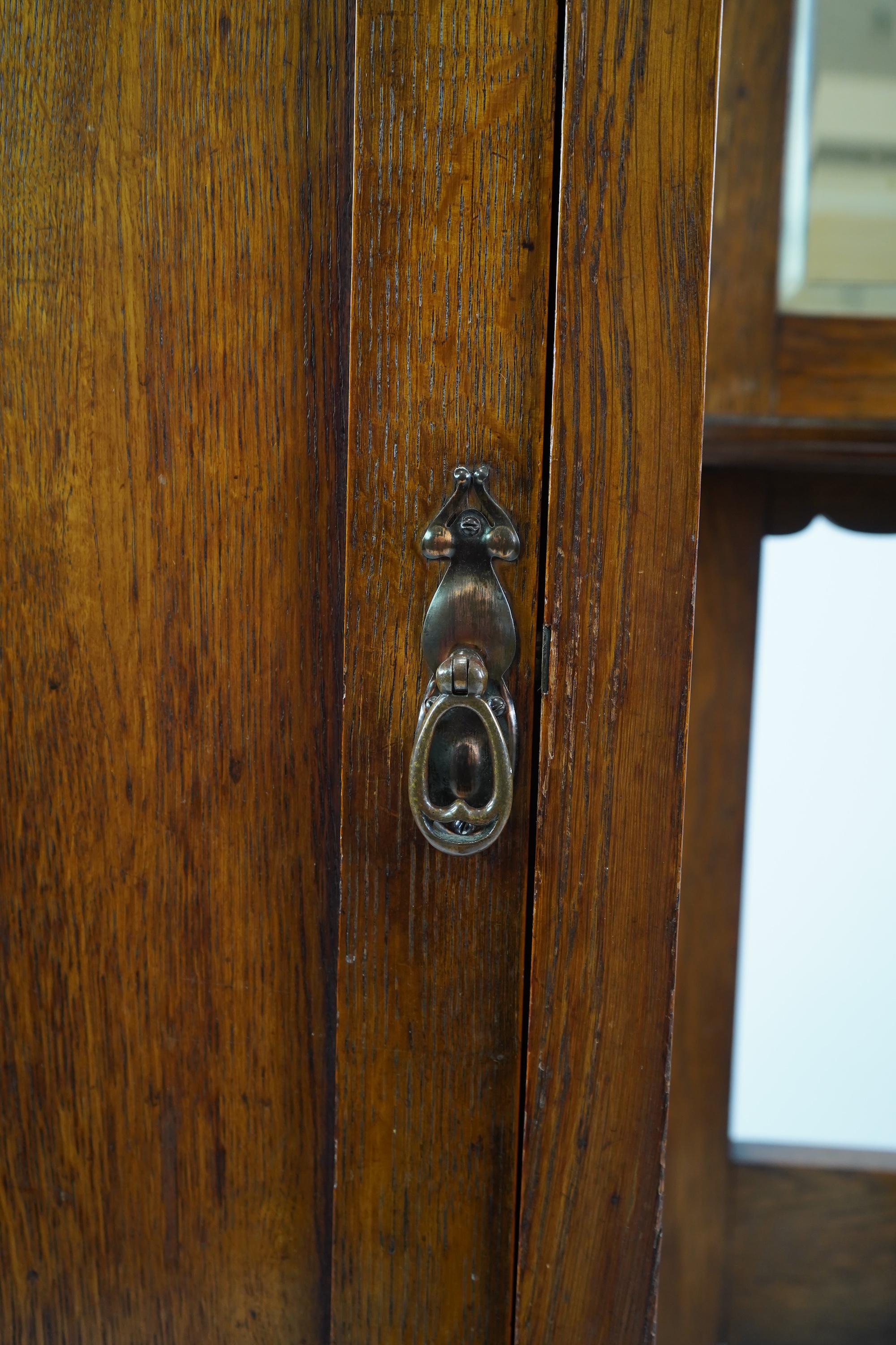 Manner of Liberty & Co: An Arts and Crafts embossed copper mounted oak hall cupboard